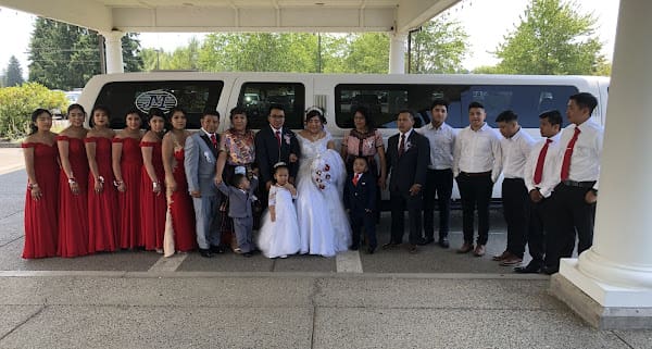 Hispanic wedding party posing with a luxury limo in Portland.